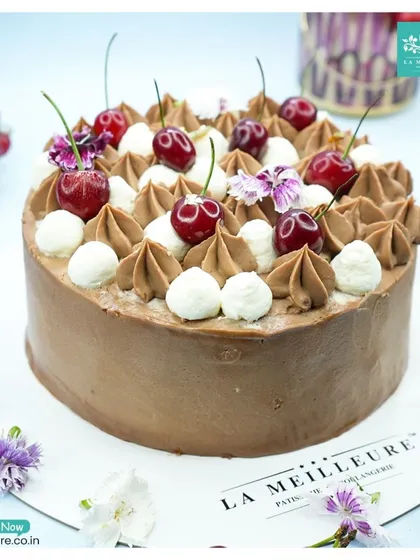 A closer look at our classic Black Forest cake, surrounded by fresh cherries and flowers that highlight its key ingredients.
