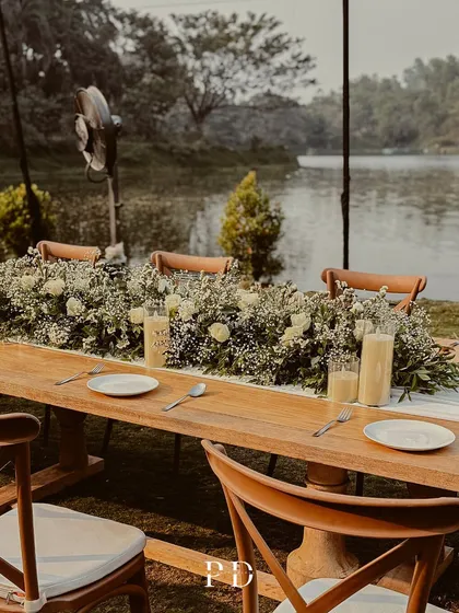 A close-up of the lakeside dinner tablescape. The lush runner of white roses and greenery, paired with simple, elegant place settings, creates a fresh and romantic look.