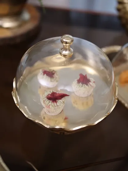 A close-up of our Gold Scallop Dessert Stand with Glass Cloche, holding delicate cupcakes. This piece blends vintage charm with bold elegance, making it a true showstopper.