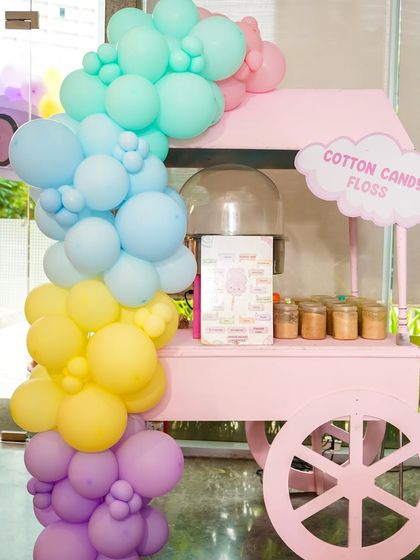 A pink cotton candy cart decorated with a pastel balloon garland, perfectly matching the Hello Kitty theme.
