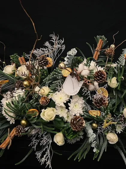 A serene, winter wonderland-inspired centerpiece. This arrangement marries the purity of white roses and cotton with the natural beauty of green pine foliage, cinnamon, and dried oranges, evoking the stillness of a misty winter walk.