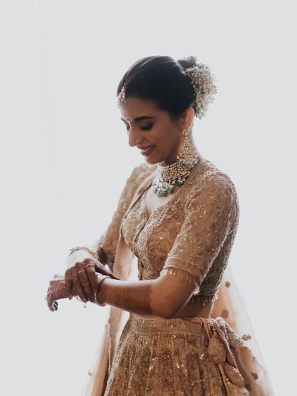 A beautiful silhouette shot. The soft light highlights her profile and the delicate details of her bun and lehenga.