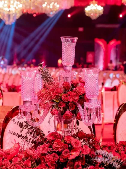 A duplicate of image 38, this photo provides a detailed look at a guest table centerpiece, where a crystal candelabra rises from a bed of lush red roses.