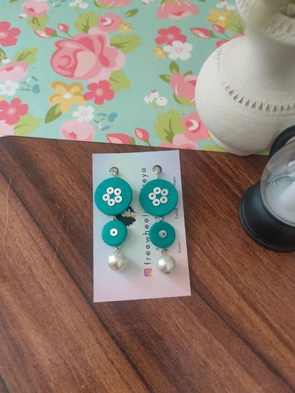 These tiered fabric earrings with pearl drops are a modern and chic design. They are available in pink, black, and teal, and are incredibly lightweight and comfortable.