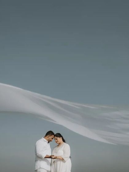 A beautiful, airy portrait of a couple under a flowing white cloth against a clear blue sky, creating a feeling of freedom and love.