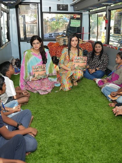 Our co-founders, Kamakshi and Vishala, lead a book reading of 'Jungle Jugalbandi' for children inside the 'Sound Space on Wheels' bus. The cozy, green-floored interior creates a perfect learning environment.