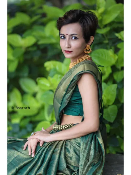 A profile shot of the model in the green saree, showing the elegant fall of the fabric and the contrast with her short hair.