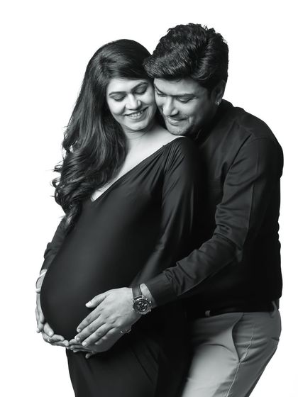 A classic black and white maternity portrait. The soft lighting and the couple's happy expressions create a timeless and joyful image.