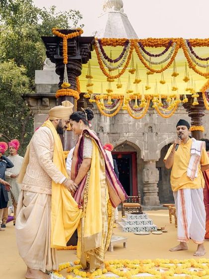 A Maharashtrian wedding ceremony held in front of a 300-year-old Ganesh temple. This image captures the 'antarpat' moment, just before the couple sees each other, highlighting the rich traditions and divine setting.