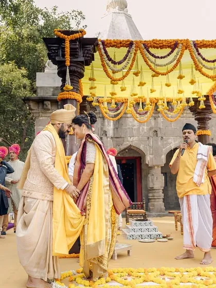 A Maharashtrian wedding ceremony held in front of a 300-year-old Ganesh temple. This image captures the 'antarpat' moment, just before the couple sees each other, highlighting the rich traditions and divine setting.