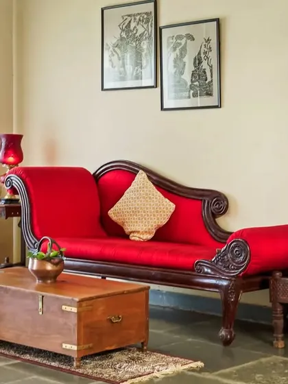 A traditional red divan and a vintage wooden chest used as a coffee table. This composition at Villa Magnolia highlights the beauty of classic Indian furniture and decor.