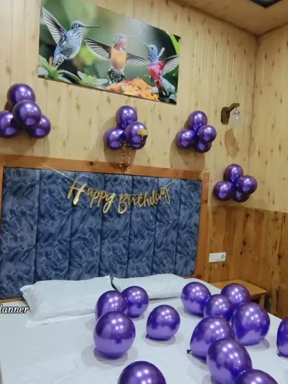 This view shows the "Happy Birthday" banner above the bed, surrounded by cheerful purple balloon clusters. It's a simple and effective way to wake someone up to a wonderful surprise.