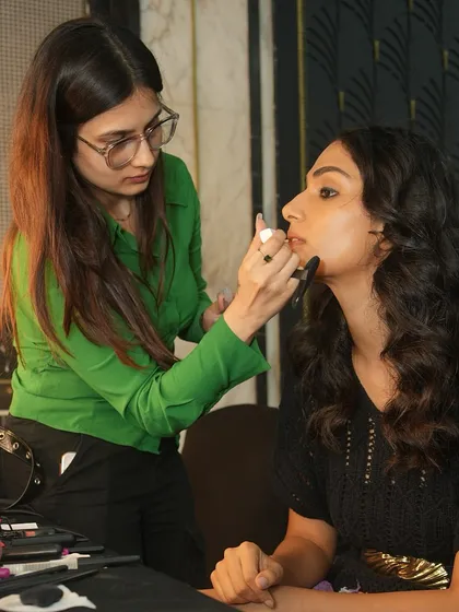 A student artist applies the final touches to a model's lips backstage at Bombay Times Fashion Week. Precision and focus are key in this fast-paced environment.