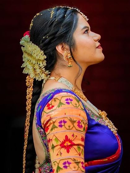A profile shot of a bride showcasing her traditional South Indian hairstyle, complete with a long, decorated braid and fresh flowers.