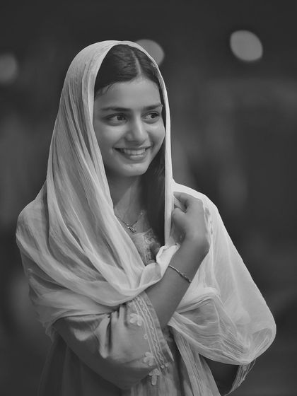 A stunning black and white portrait with a dupatta over her head. The monochrome tones and her serene smile give this shot a timeless, classic, and almost spiritual feel.