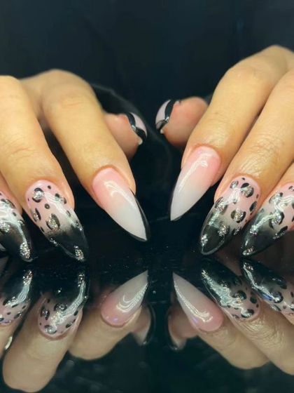 A fierce ombre design on stiletto nails, blending from a nude base to a black tip with a leopard print overlay.
