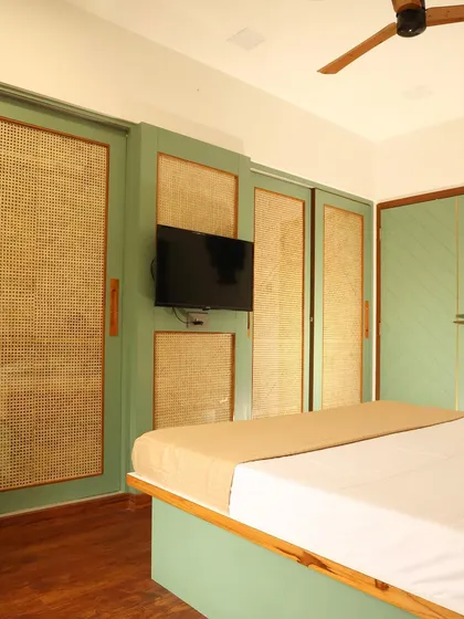 This master bedroom combines a green and natural wood theme, with sliding wardrobe doors made of cane to keep the look light and airy.
