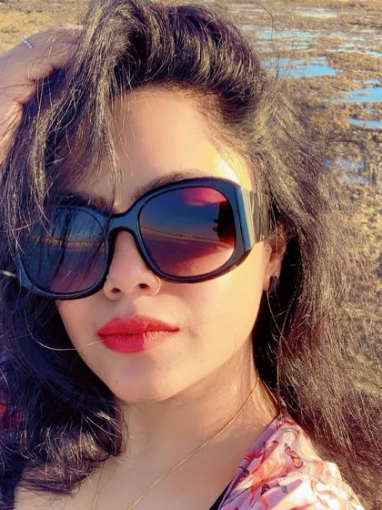 A sun-kissed selfie on the beach, with oversized sunglasses and a red lip adding a touch of glamour to the vacation look.