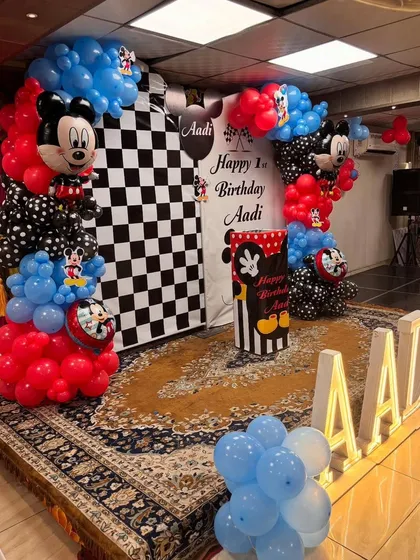 The main stage area for the Mickey Mouse party, with a custom-wrapped pedestal for the cake and balloon arches.