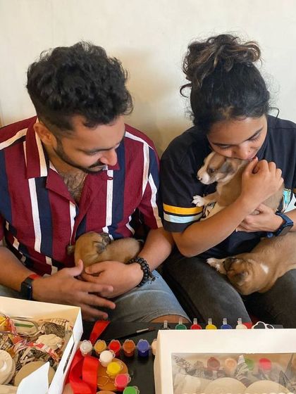 A couple shares a sweet moment, each cuddling a tiny newborn puppy during a pottery painting session.