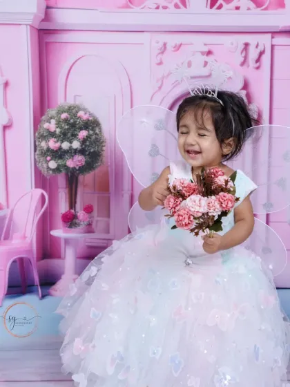 Giggles and magic. This candid shot captures the pure happiness of a toddler playing dress-up in a whimsical setting.