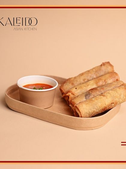 Crispy vegetarian spring rolls served in a biodegradable tray with a side of dipping sauce. They are a perfect choice for a light snack or to start a larger vegetarian feast.