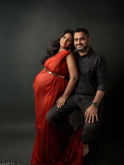 A powerful and classic pose. The contrast of the red dress against the dark background and his black shirt is striking.