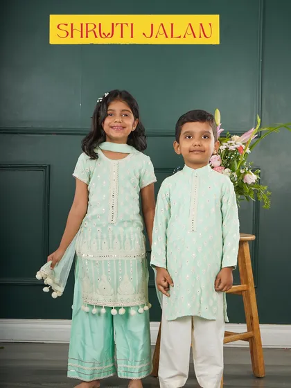 A classic look in mint green. The sister's sharara with pom-pom trim and the brother's simple kurta are both made with the same beautiful fabric.