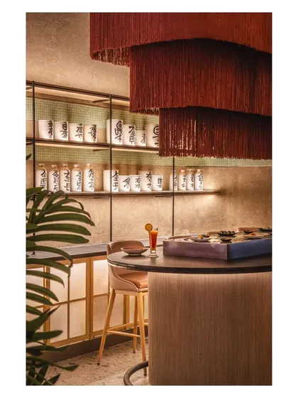 The cascading tassel light at the sushi bar adds a whimsical touch, making this corner warm and inviting. We paired it with pots scripted with Japanese phrases to lend a touch of tradition to the modern setting.