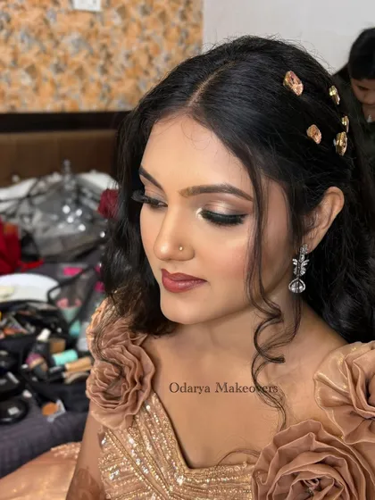A close-up of the reception makeup. The focus is on a bronze smokey eye and a glossy nude lip, a classic combination that looks stunning with her golden gown.