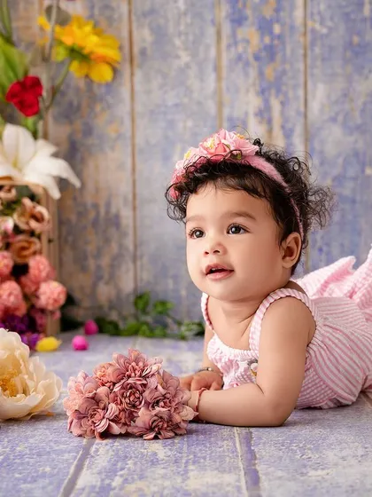 A lovely tummy-time portrait of baby Mahira, surrounded by a crate of beautiful, colorful flowers.