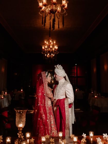 A regal portrait set in a candlelit hall at Suryagarh. The warm lighting and opulent surroundings create a rich, intimate atmosphere as the couple shares a quiet look.
