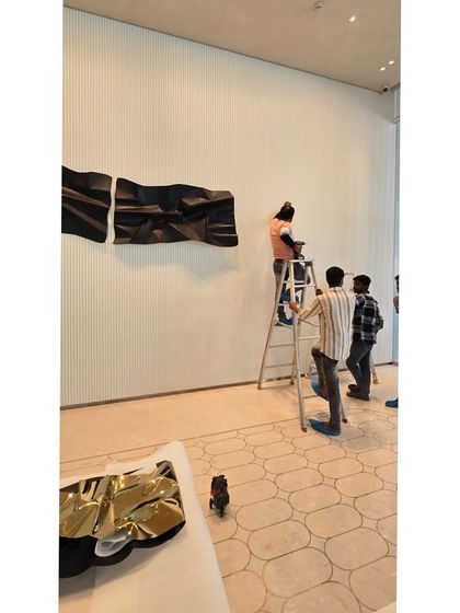 A wide shot of the installation in progress, showing the scale of the artwork and the effort involved.