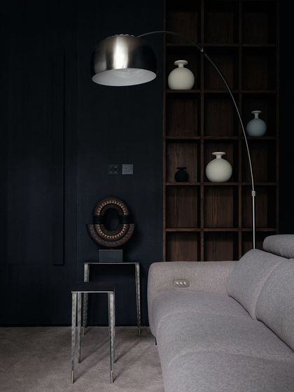 The family room is a cozy, intimate space designed for movie nights. The dark walls, deep shelving, and comfortable grey sofa create a perfect environment for relaxation.