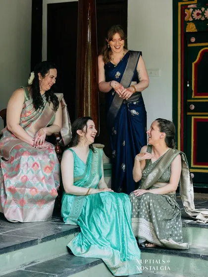 Bridesmaids from the West, beautifully dressed in sarees, share a laugh on the steps of our heritage building.
