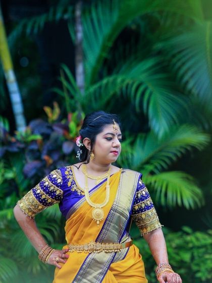 A beautiful bride in a yellow and blue Kanjeevaram saree, posing outdoors. This shot was likely taken during a pre-wedding ritual.