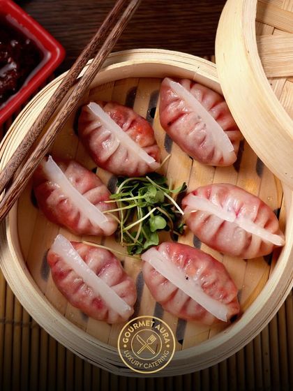 A bamboo steamer is opened to reveal perfectly crafted chicken dumplings, ready to be served. Our live dim sum stations are a highlight at any event.
