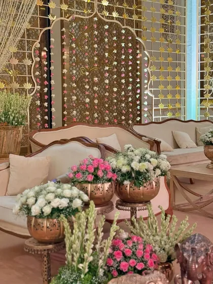 A comfortable and elegant lounge area, set against a backdrop of golden screens and hanging flowers. The elephant figurines add a touch of traditional charm.