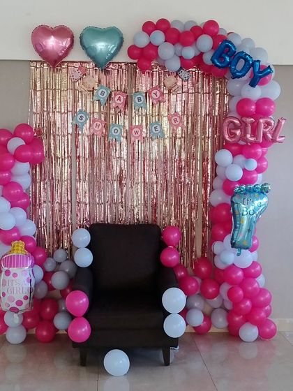 A "Boy or Girl" gender reveal party setup with a pink and blue balloon arch and a shimmer backdrop.