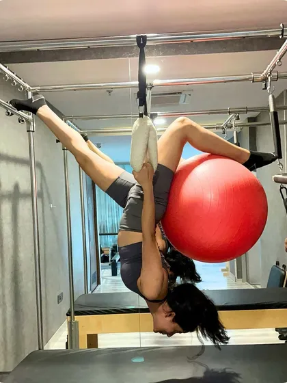 Defying gravity on the Pilates Cadillac. This advanced apparatus allows for incredible stretches and strength building exercises that decompress the spine and build full body power.