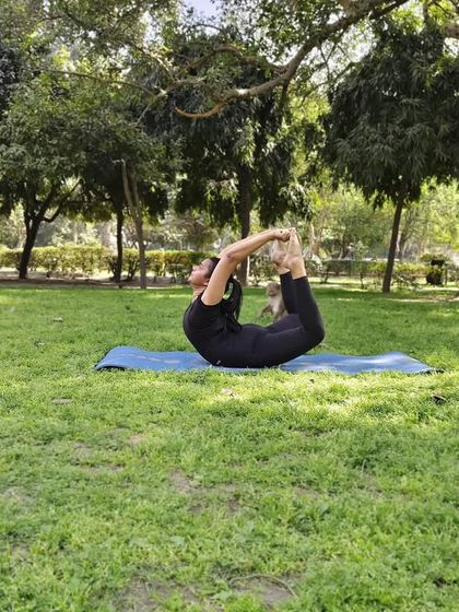 A student performs Dhanurasana (Bow Pose) in the park. This back-bending asana opens up the chest and strengthens the diaphragm, which is highly beneficial for improving lung capacity and managing symptoms of bronchitis.