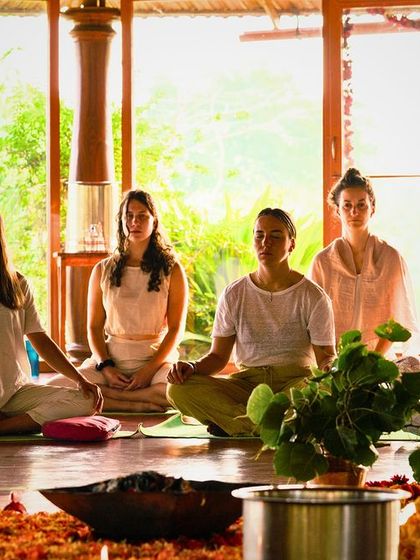 Students sit in quiet contemplation during a Puja ceremony. The sacred fire and chanting help to purify the space and focus the mind, creating a powerful container for the deep work of yoga teacher training.