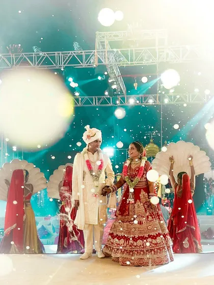 From "Yes" to "Forever," every detail is crafted with a touch of magic. This dreamy shot captures the couple's Varmala moment amidst beautiful lighting and traditional dancers.