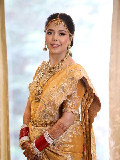 A full-length view of the South Indian bride, her traditional hairstyle perfectly complementing the silk saree and temple jewelry.