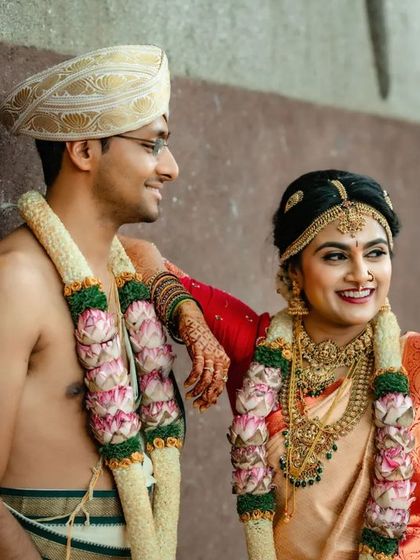 A relaxed and happy portrait of a couple, leaning against a wall and sharing a laugh after their wedding ceremony.