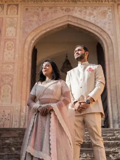 A regal, confident pose on the steps of a historic Jaipur monument. The couple stands side-by-side, their posture exuding grace and strength.