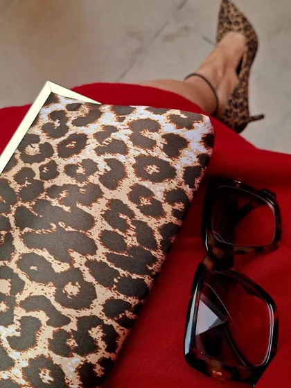 Embrace your wild side. A close-up on leopard print accessories, a classic clutch and pointed-toe heels, paired with a bold red dress. This timeless print adds a touch of fierceness to any outfit.