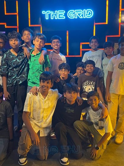 A group of kids posing for a photo in front of our neon logo.