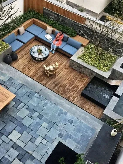 A multi-level terrace designed for versatile outdoor living. This concept demonstrates intelligent space planning, with a raised wooden deck for lounging, a lower stone patio for dining, and cascading water features that add movement and tranquility to the urban environment.