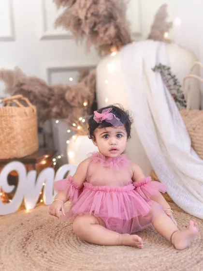 A lovely portrait of a one-year-old in a boho-chic setup. The natural textures and warm lights create a cozy and inviting atmosphere for a first birthday shoot.